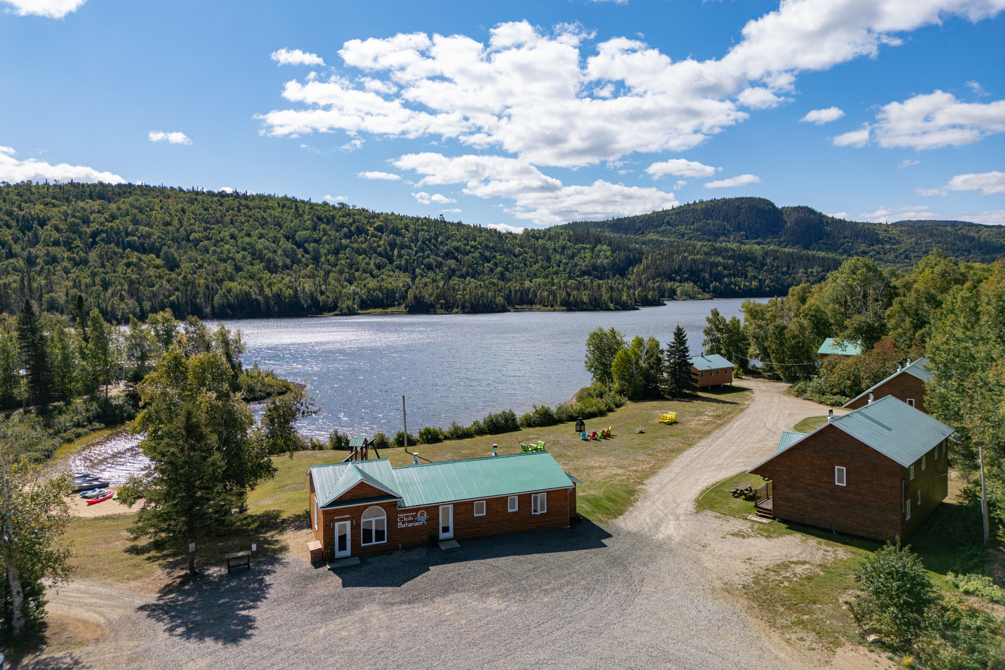 Vue aérienne de chalets en bois au bord d'un lac entouré de forêt dans la pourvoirie du Club Bataram