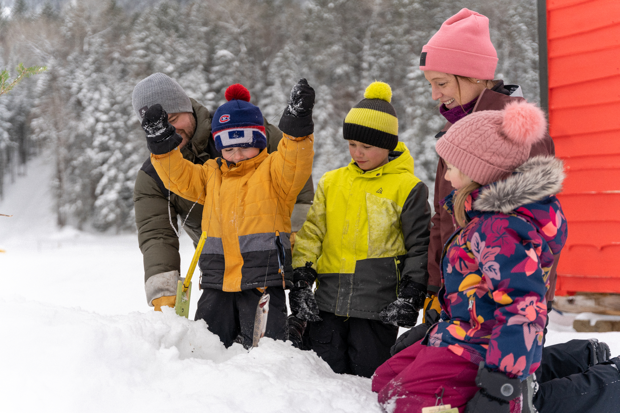 Enfants jouant dans la neige avec des adultes, explorant la nature hivernale de Charlevoix en famille