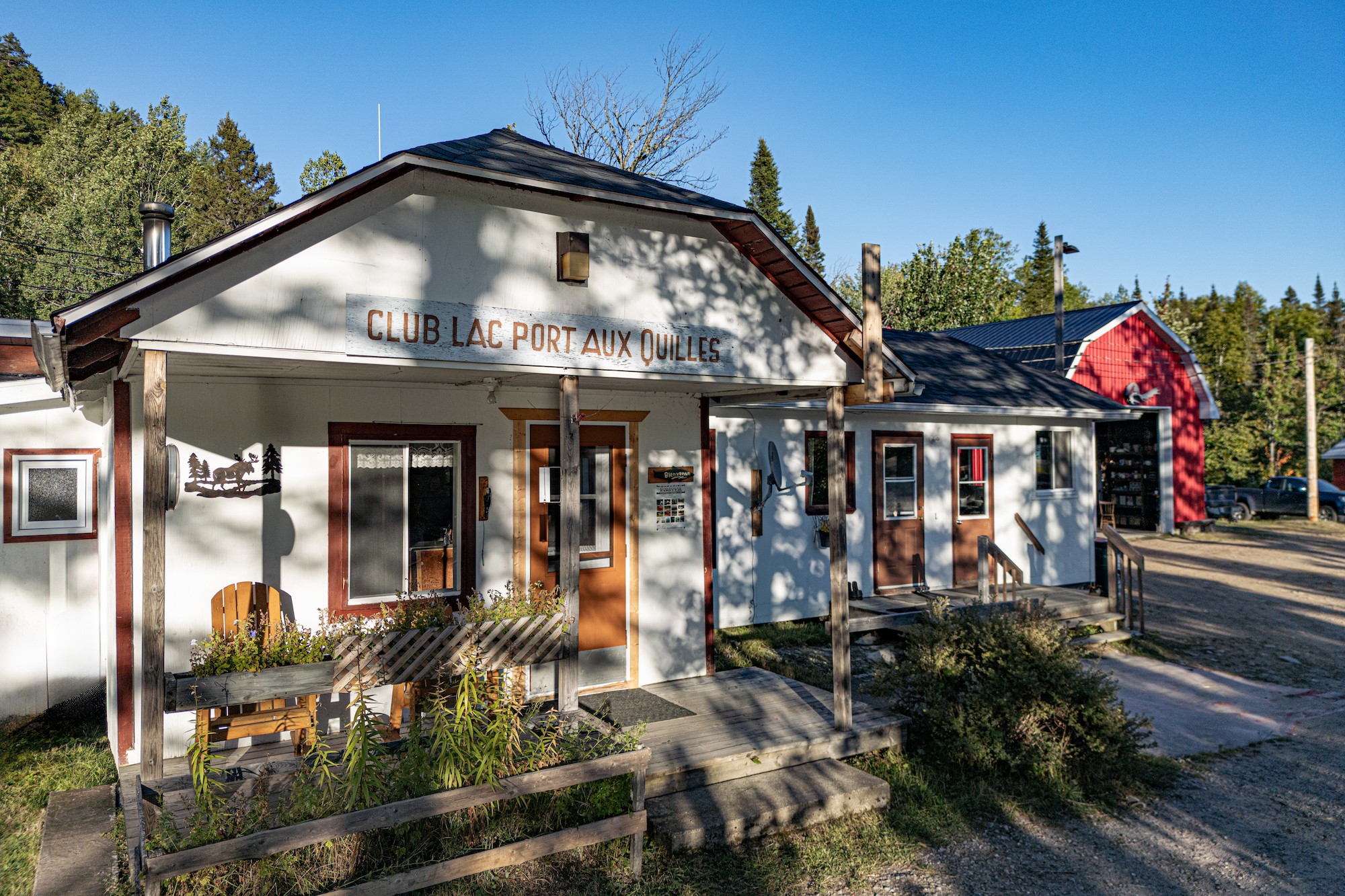 Club Lac Port aux Quilles building with outdoor seating and trees, set in a nature-rich area near Charlevoix mountains