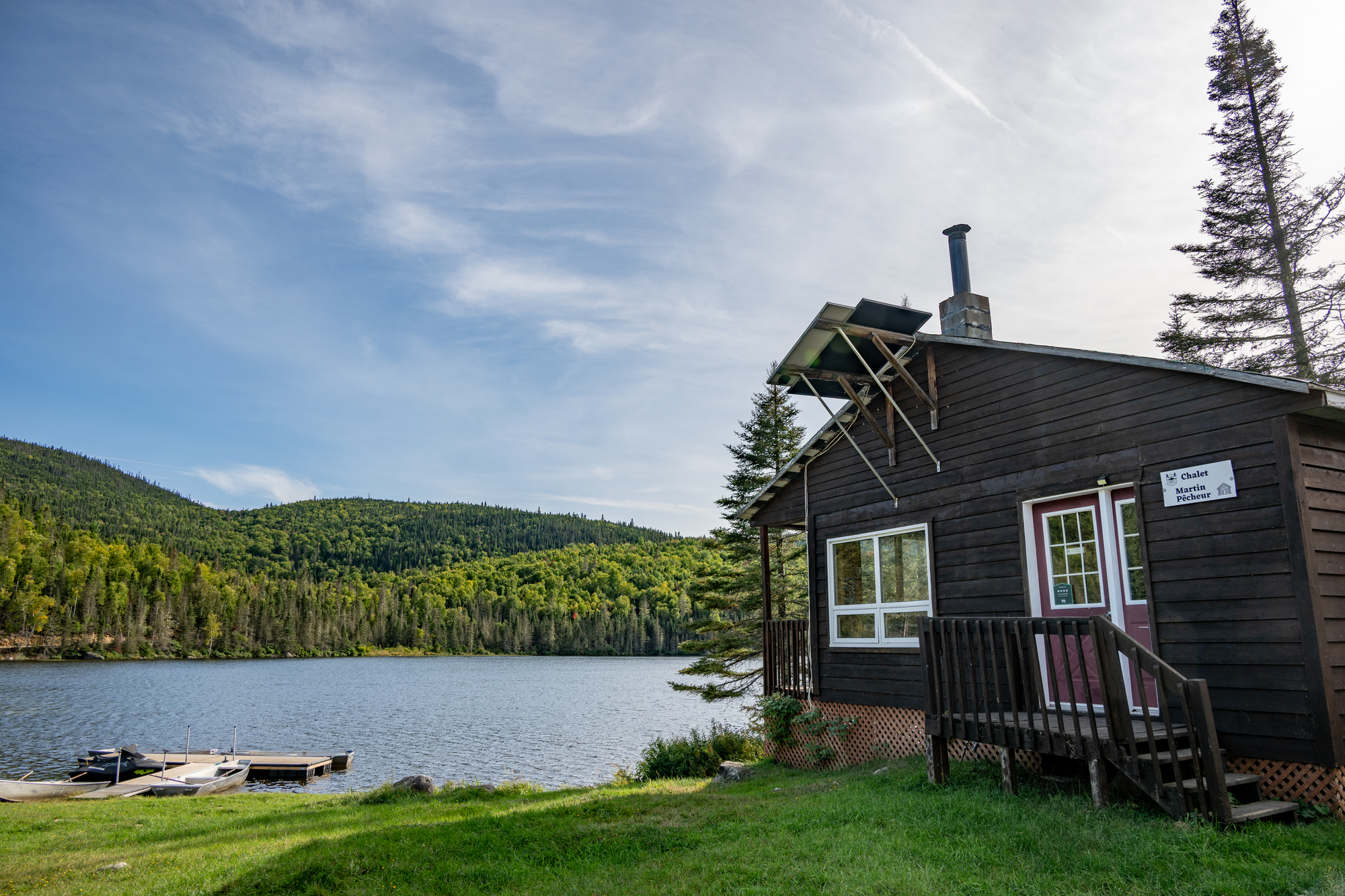 Chalet en bois au bord d'un lac entouré de collines verdoyantes à la pourvoirie Domaine du Lac Brouillard