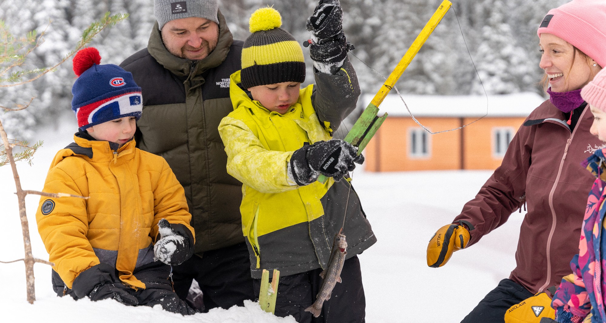 Famille en train de pêcher sur la glace, enfants utilisant des cannes à pêche, ambiance hivernale joyeuse au Domaine Le Pic-Bois