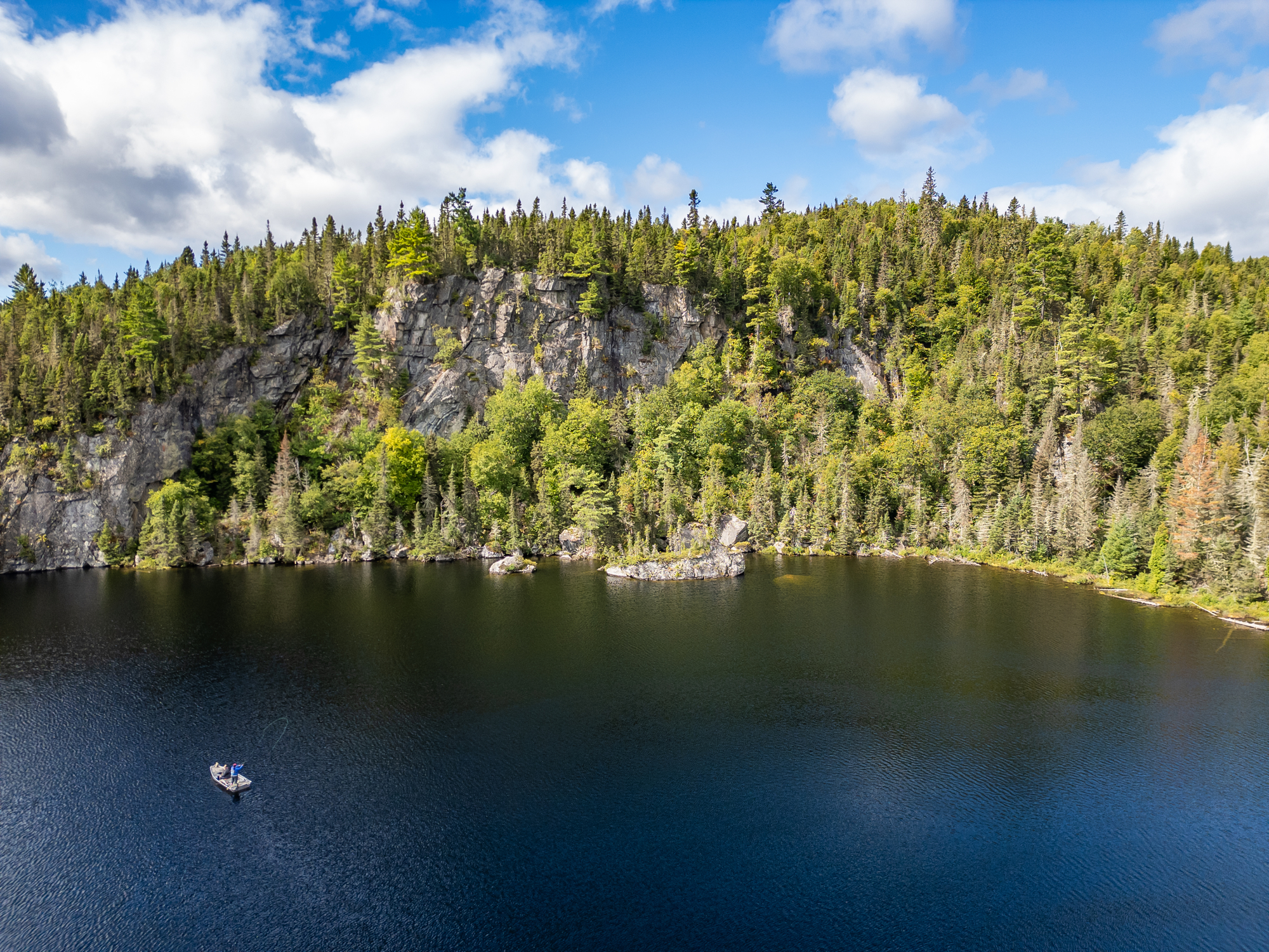 Scenic view of Lake François surrounded by lush forests and cliffs with a small fishing boat on the water