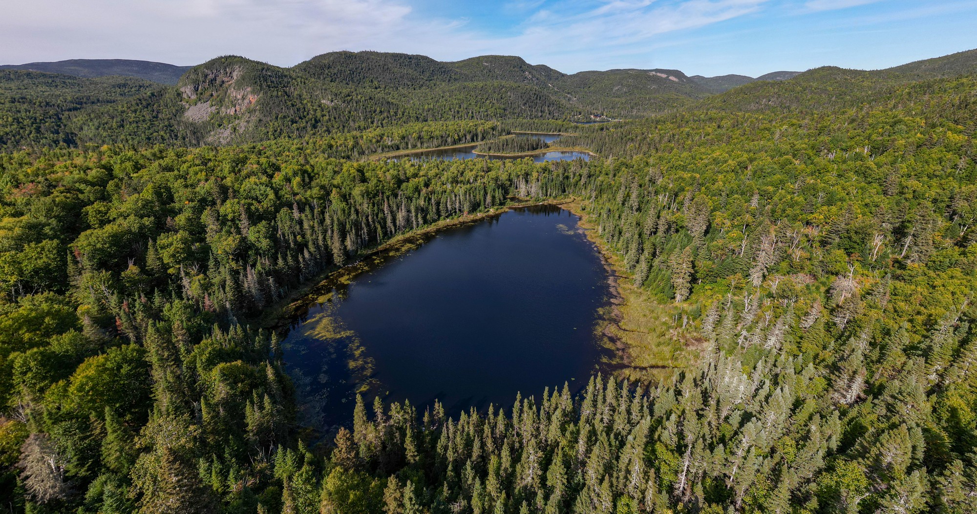 Vue aérienne d'un lac entouré de forêts denses dans la région sauvage du Charlevoix, idéal pour la chasse