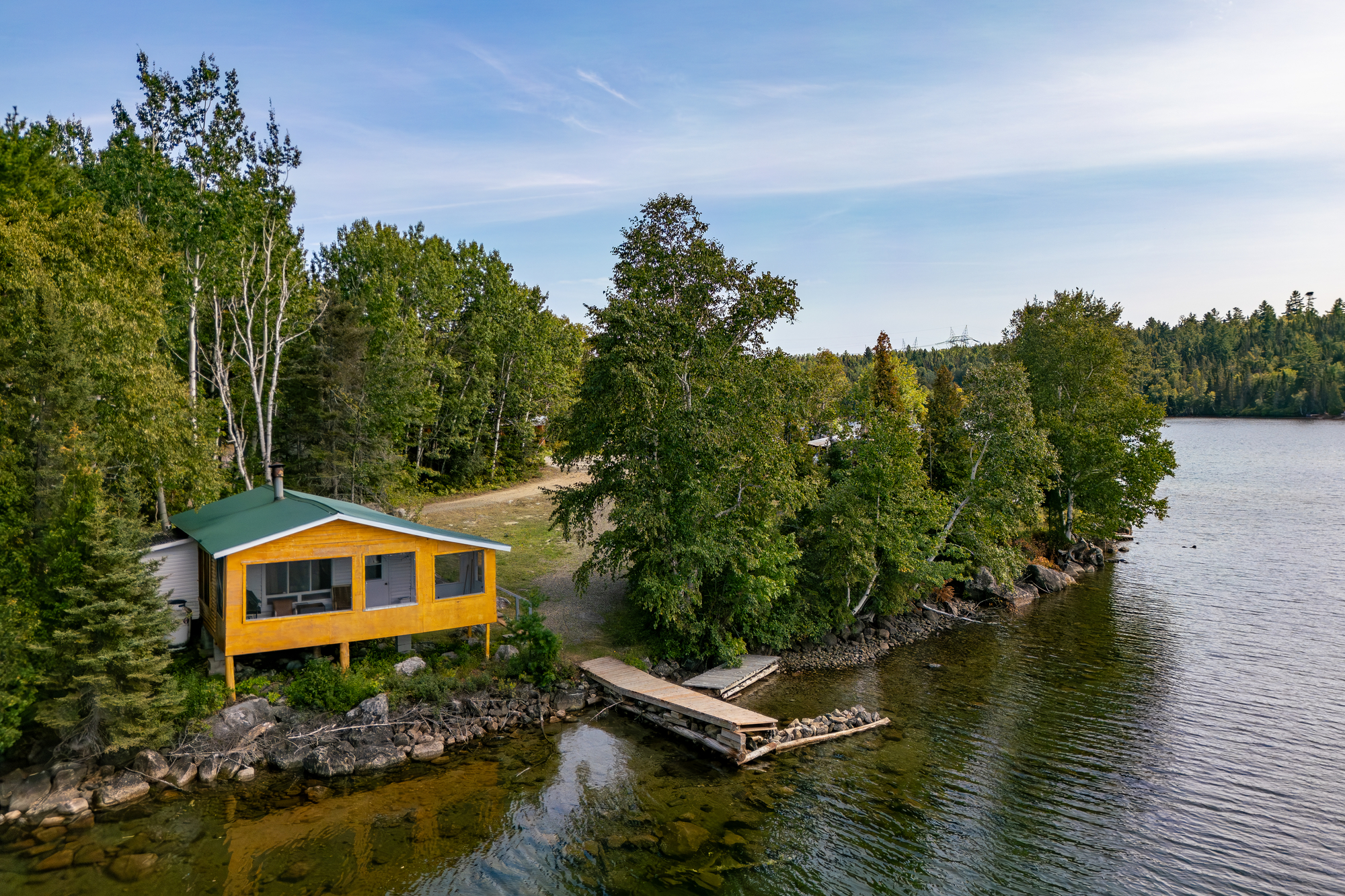 Chalet au bord de l'eau entouré d'arbres, avec un quai et un accès à la nature à la Pourvoirie des Lacs Roger et Faucille