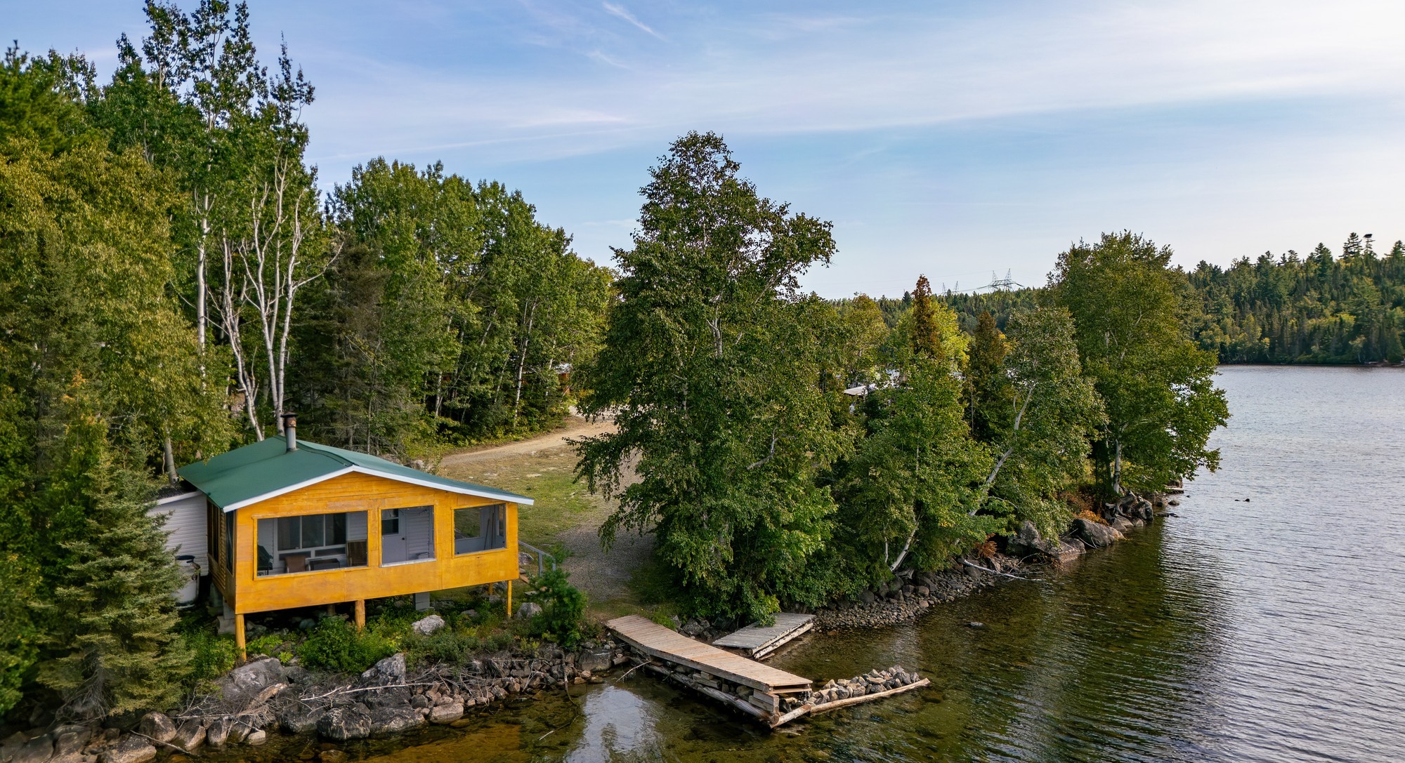 Chalet en bois jaune au bord d'un lac entouré d'arbres dans la région de Charlevoix