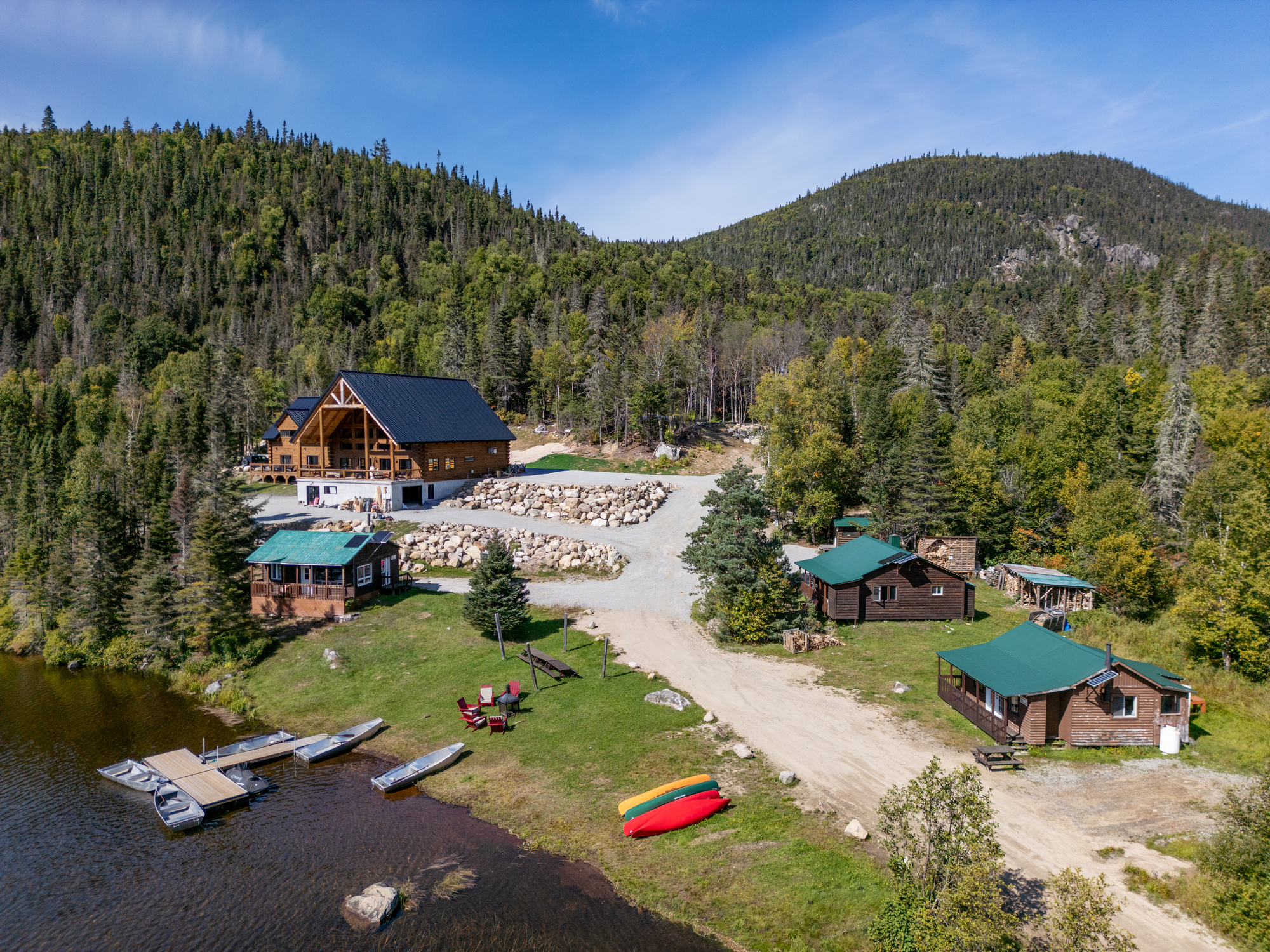 Vue aérienne du Domaine du Lac Brouillard avec chalets, embarcations sur le lac et paysage forestier environnant