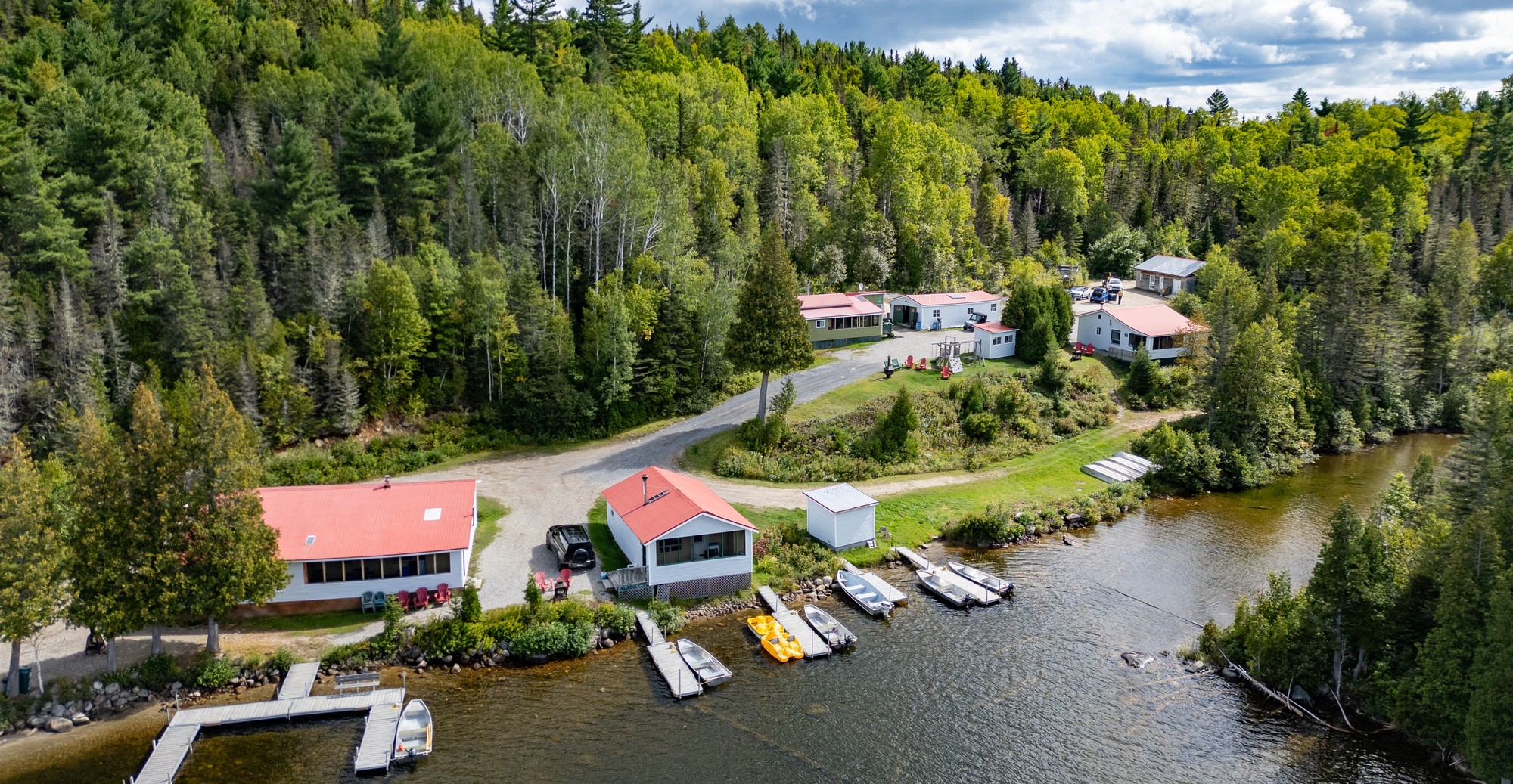 Vue aérienne de la Pourvoirie Humanité avec chalets et embarcations au bord du lac François, entourée de forêt verdoyante