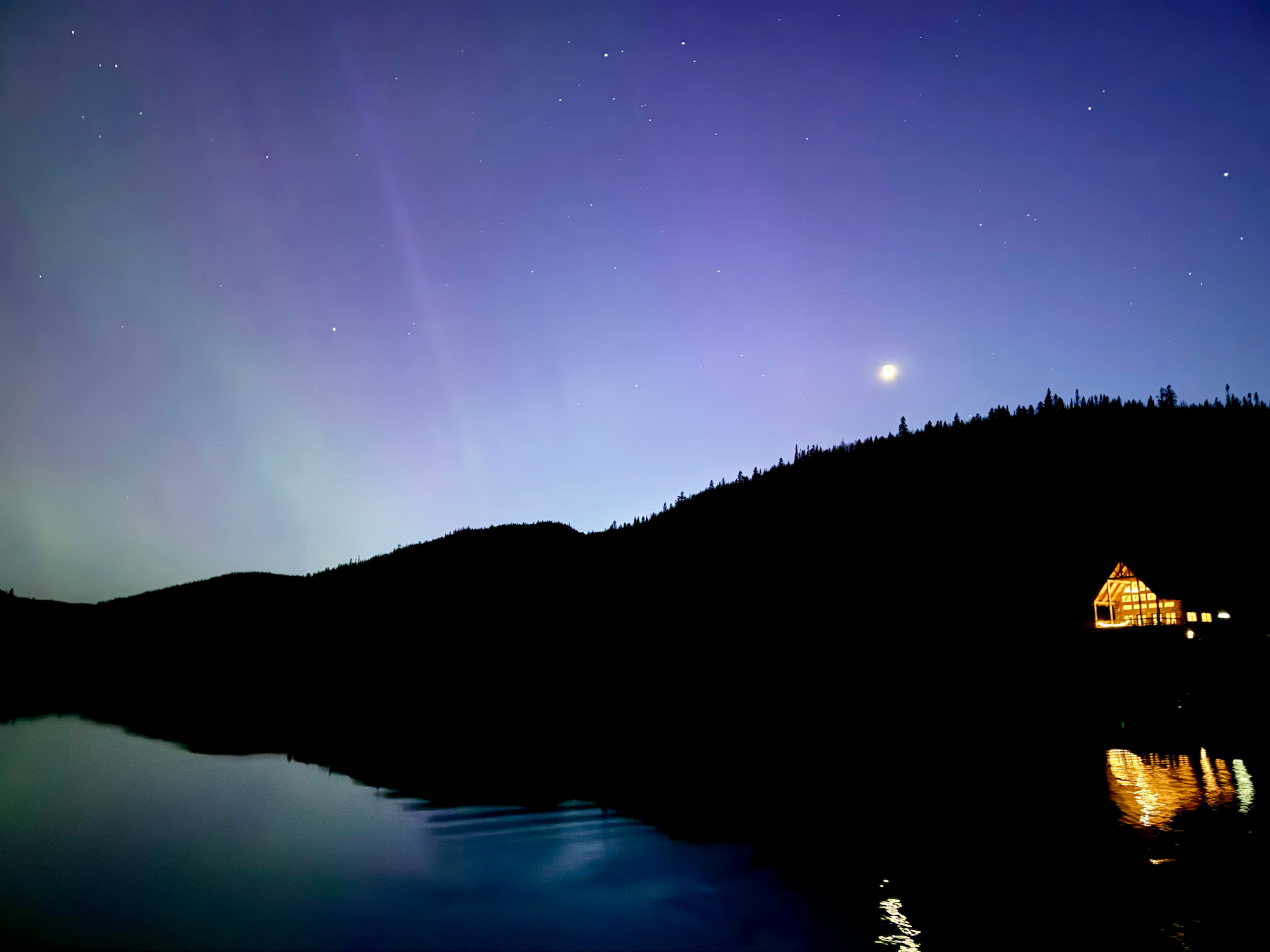 Aurores boréales au-dessus du lac et d’un chalet illuminé au Domaine du Lac Brouillard, Charlevoix